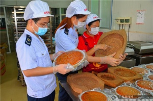 胜香食品厂负责人罗来胜正在向大家展示8斤重月饼的饼印.