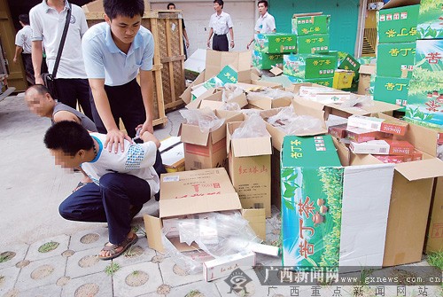 执法人员抓获两名犯罪嫌疑人后,将藏在苦丁茶纸箱里的假烟起出.