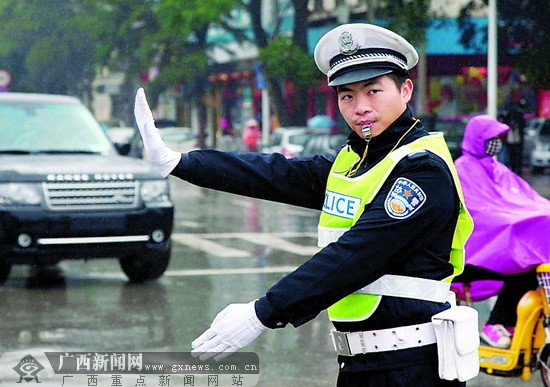 上午11时,南宁民族古城路口,交警周军君在雨中指挥过往车辆.