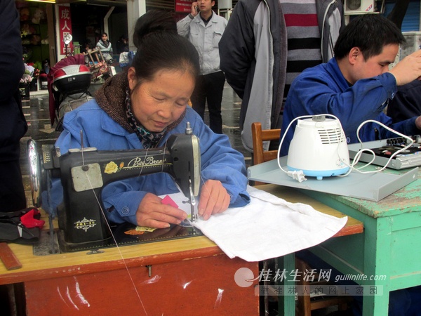 在三里店大圆盘,50多岁的谢芬阿姨用自家的缝纫机为市民免费缝补衣物.