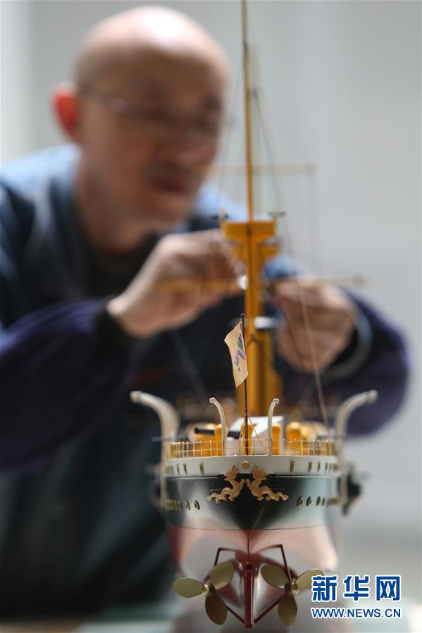 手工船模制作人李民对即将交货的致远舰模型进行最后检查
