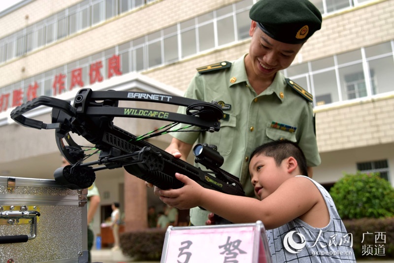 在武警河池市支队警营开放日,一名小朋友在了解弩的使用方法(高东风