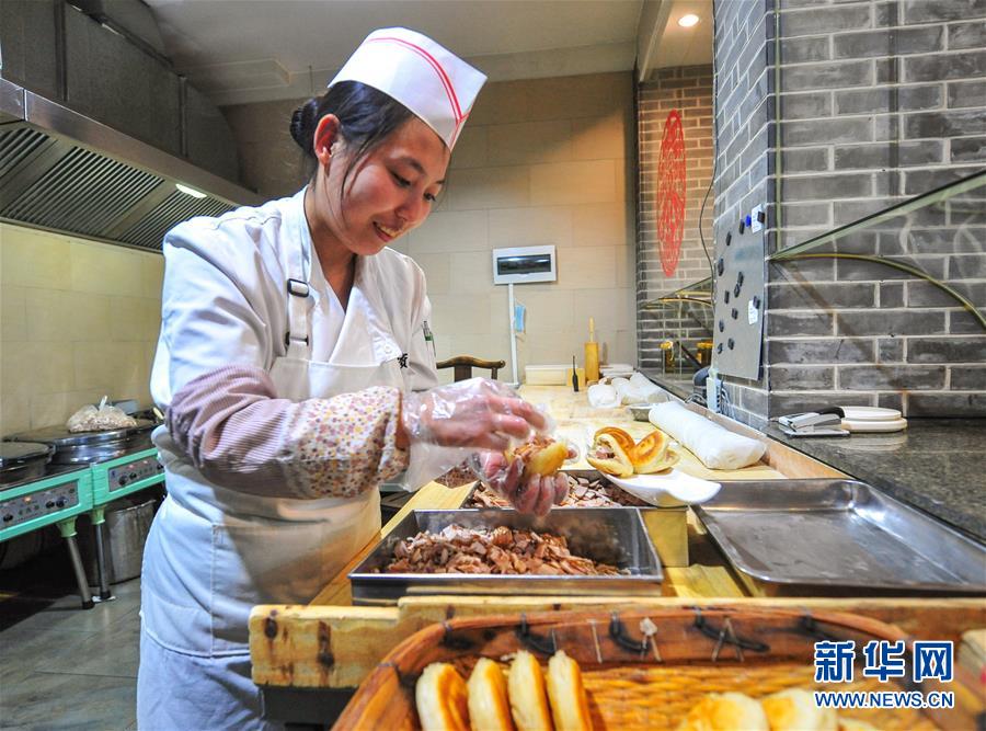 2月2日,赤峰市宴宾楼餐厅的厨师将熏肉夹入刚出锅的烧饼内.