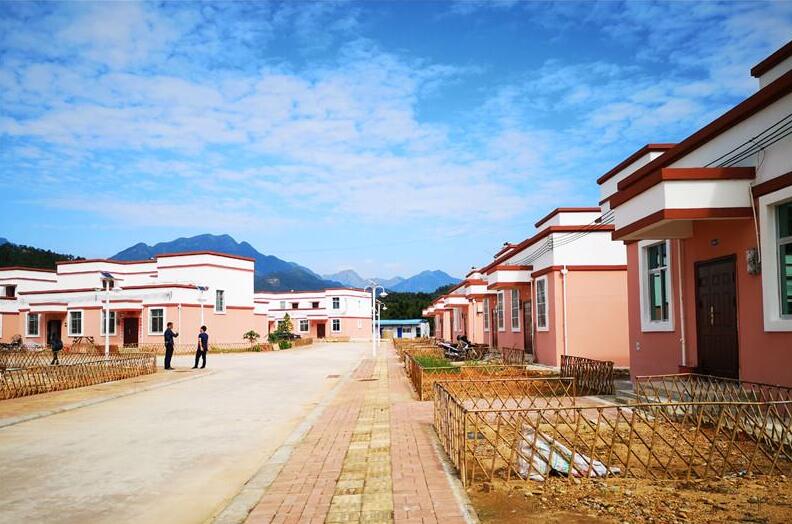 图为防城区那良镇易地扶贫搬迁工程那巴村集中安置点。 本报记者 朱新华 摄 记者见到项光情的时候,他正抱着孙子在小区里散步。他嘴里哼着歌,走过一家又一家门前的微菜园。 项光情现在居住的小区,是防城区那良镇易地扶贫搬迁工程中的那巴村集中安置点。今年4月,作为贫困户的他带着家人告别了低矮的砖瓦房,从那巴村水车组搬进了安置小区。敞亮的楼房,门前菜园屋后花园,让这位曾经和贫困纠缠多年的老人笑得合不拢嘴。如今,他的儿子在镇上找到了一份不错的工作,而他在家里含饴弄孙,到了收获季节就回老家收香料和玉米,亦可补贴家用。