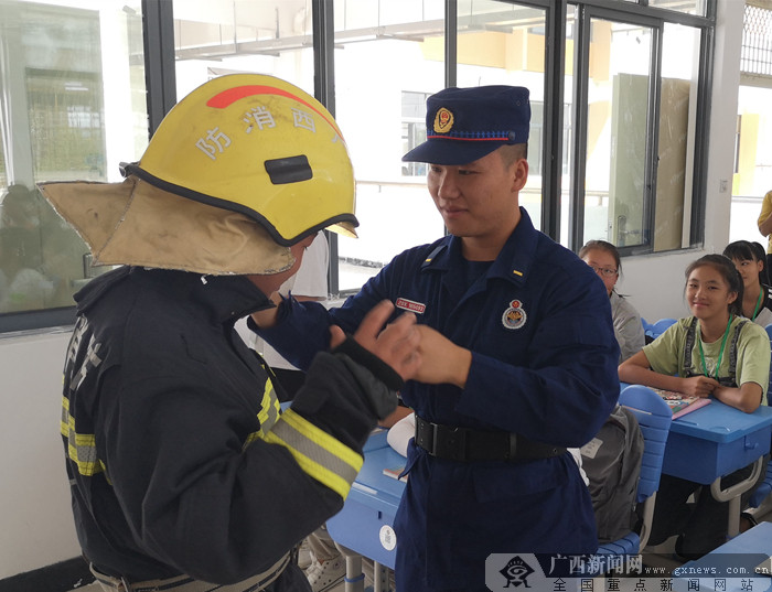 学生在消防员指导下体验穿戴消防服.通讯员 蓝丹 供图