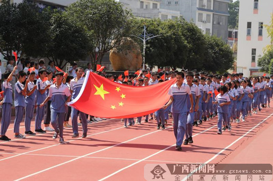 平乐县沙子中学学生手托国旗绕运动场一周.