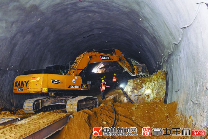 在南玉高铁良睦隧道,施工人员指挥挖掘机作业.