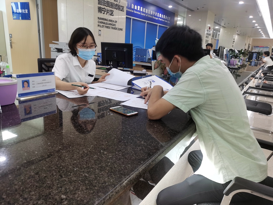 南宁片区服务大厅工作人员正在指导前来办理业务的市民填写表格。广西新