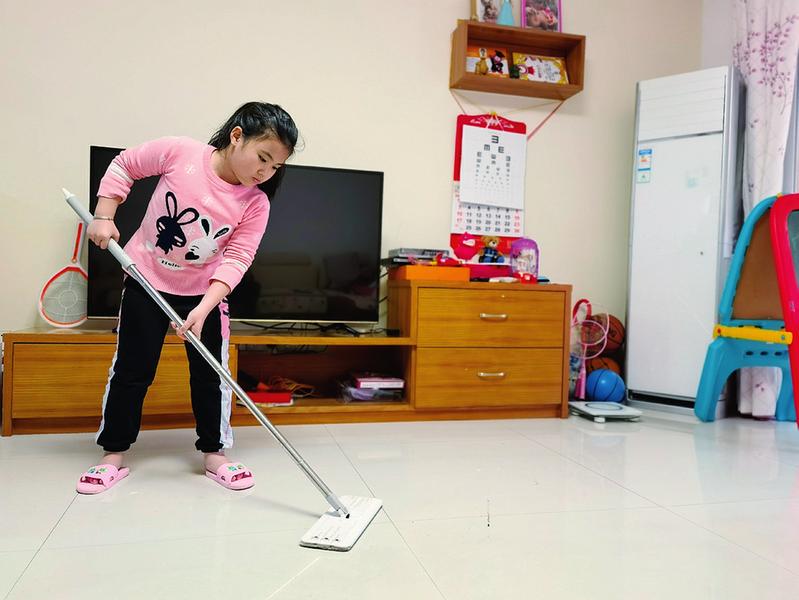 南宁市月湾路小学学生在家中拖地.学校供图