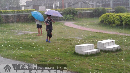 25日,崇左市江洲区突降冰雹,小朋友撑着伞玩冰雹.何朝宁摄