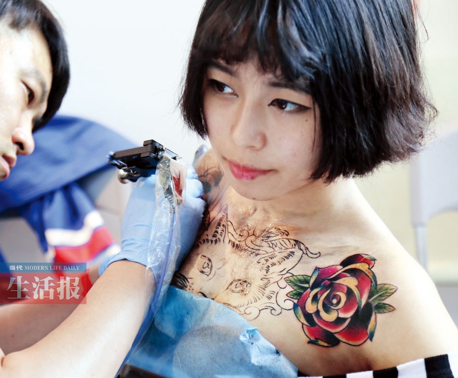 14日在南宁国际会展中心,国际顶级纹身高手为一位女士纹身.