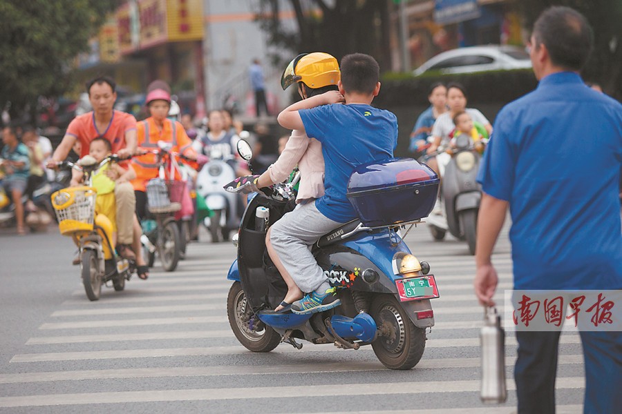 不少市民骑着电动自行车横过斑马线.