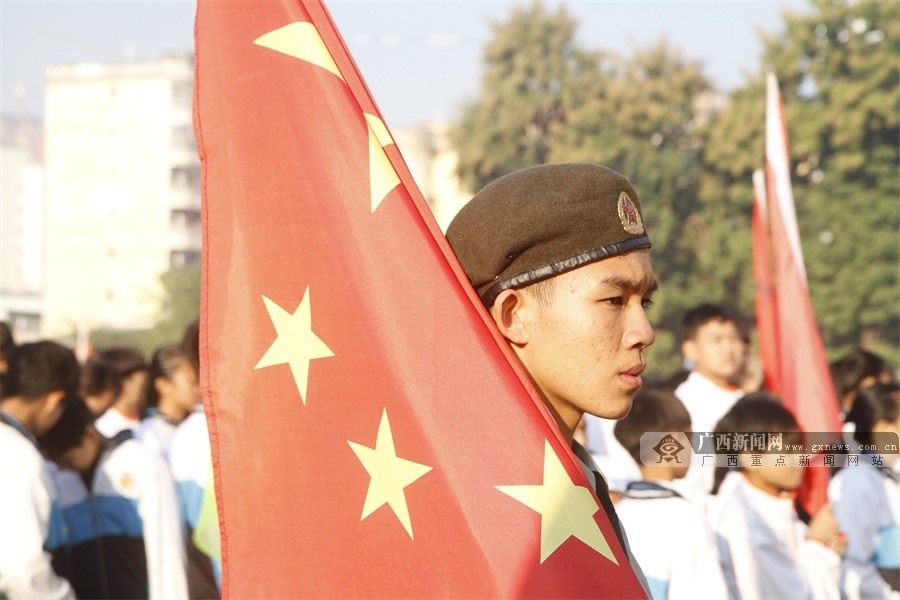 肩扛五星红旗的护旗手眼神专注.黄旸 摄校徽方阵.