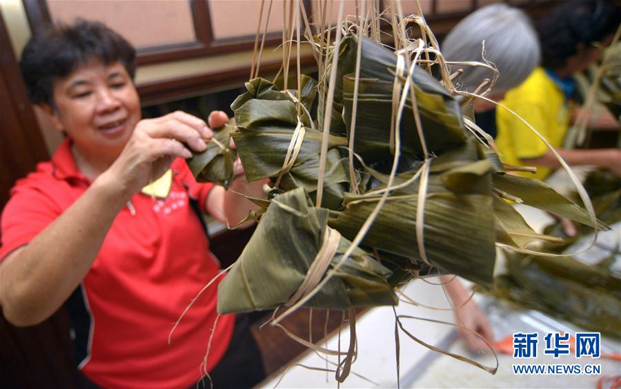 5月21日,在马来西亚首都吉隆坡,一名参赛者进行裹粽子比赛.