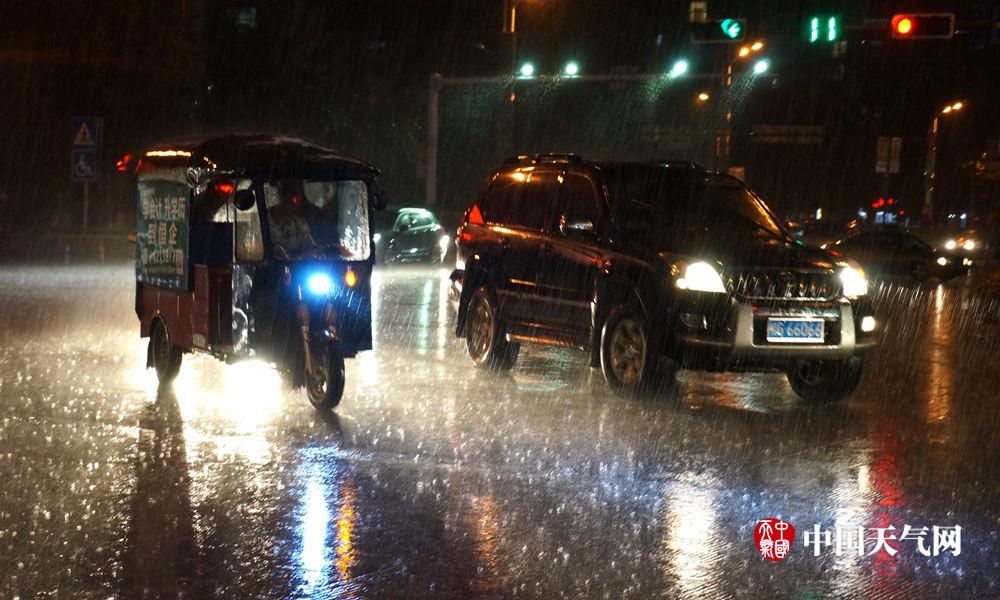 来宾夜间突下大雨 行人车辆匆匆前行