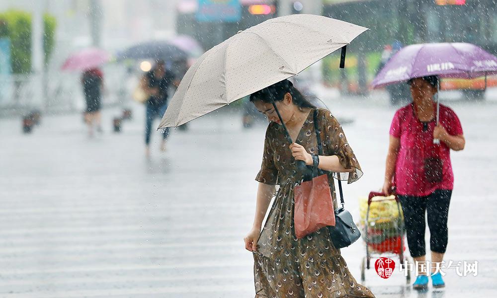 出行市民摆弄被雨水浸湿的裙子(摄影:刘英轶)