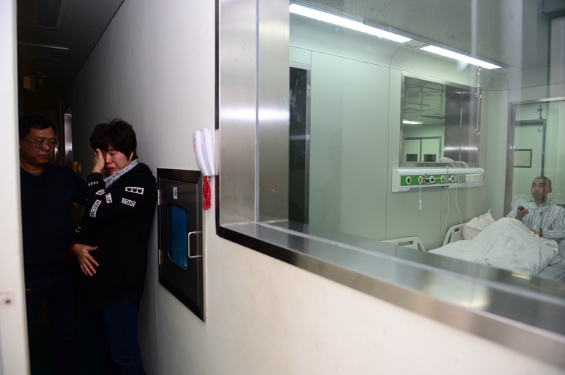 2月23日,在广西柳州市人民医院,谢雪霜在层流洁净病房探视窗口外哭泣.