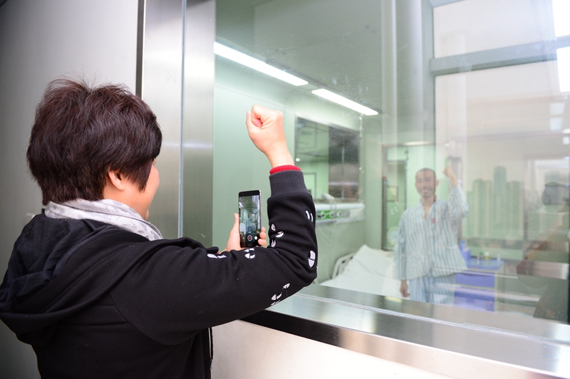 2月23日,在广西柳州市人民医院,谢雪霜在层流洁净病房探视窗口前为