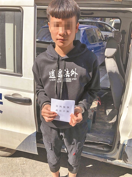 穿着"逍遥法外"衣服的嫌疑男子,手持"法网恢恢 疏而不漏"纸条拍照.