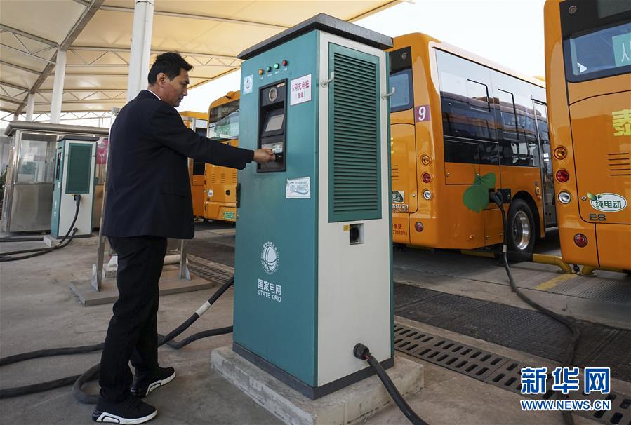 11月10日,在泰兴市公交总站,工作人员在为纯电动公交车充电.