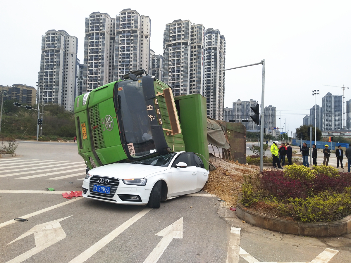 泥头车与奥迪车相撞后侧翻 车上沙石重重压住小车