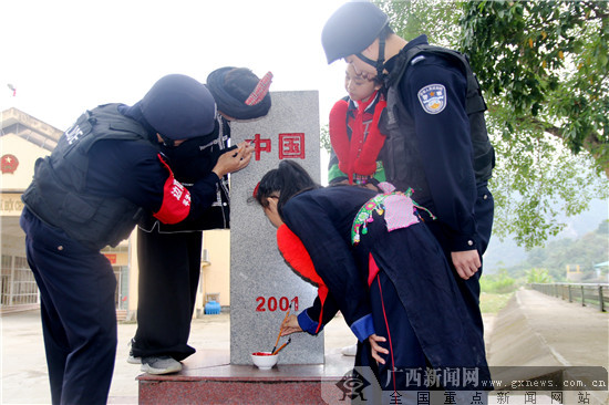 图为移民管理警察和孩子们一起为界碑描红上漆.