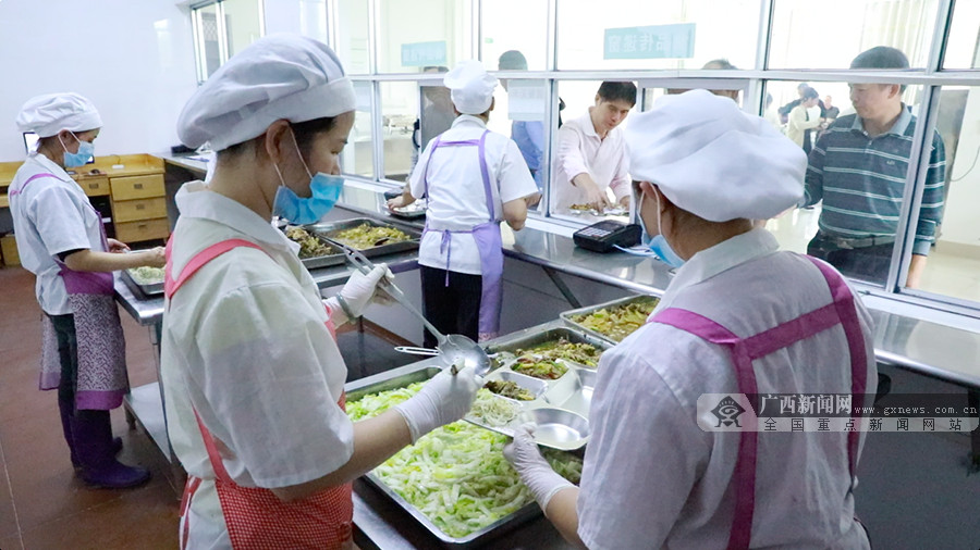食堂打饭员根据职工要求适量装菜.李伊 摄