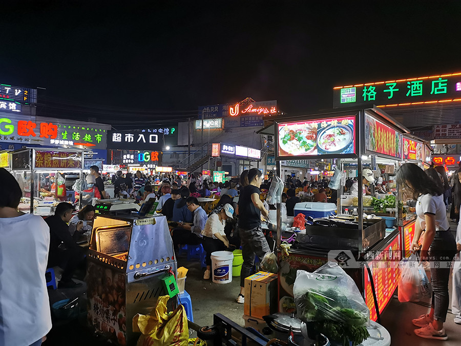 图为广西民族大学思源湖校区门口的美食街上,消费者们在夜宵摊享用