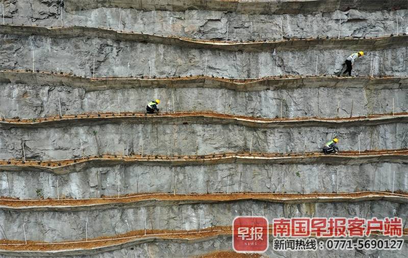 图为3月22日,工人在楼梯山山体复绿工程施工现场植树.