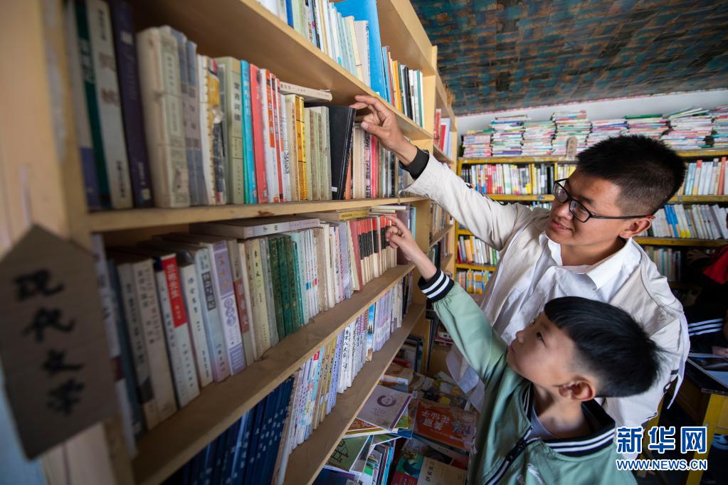 在灵丘县东窖村大学蜂乡村图书馆,张宏帅帮一位小朋友取书(4月18日摄