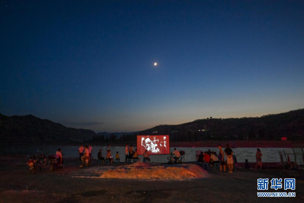 在柳林县三交镇黄河边,村民在观看露天电影(7月14日摄).