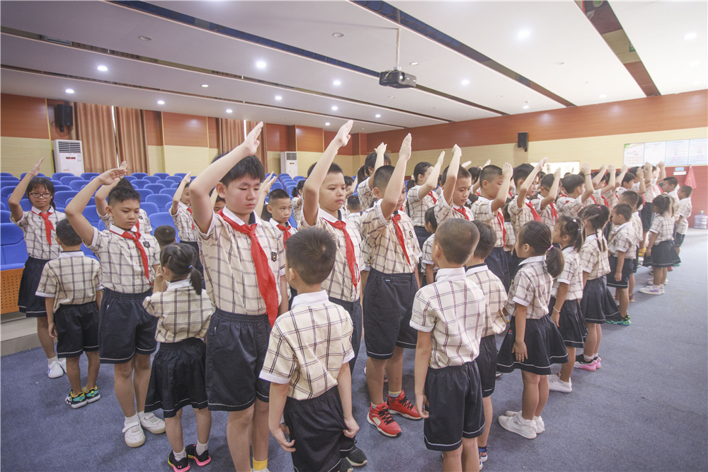 南宁市民主路小学佛子岭路校区高年级学生给一年级新生佩戴校徽.